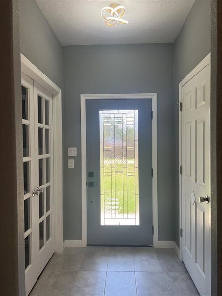 Entryway featuring light tile patterned flooring and a textured ceiling. Entryway featuring light tile patterned flooring and a textured ceiling.