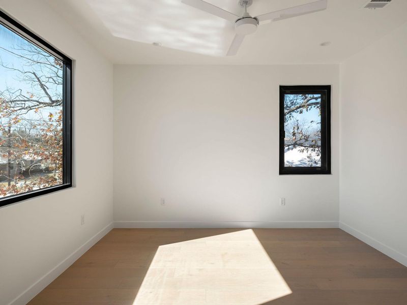 Empty room with dark wood finished floors and a ceiling fan