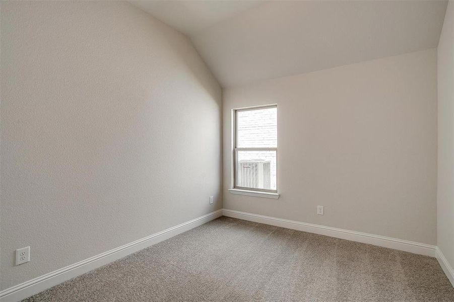 Carpeted empty room with vaulted ceiling