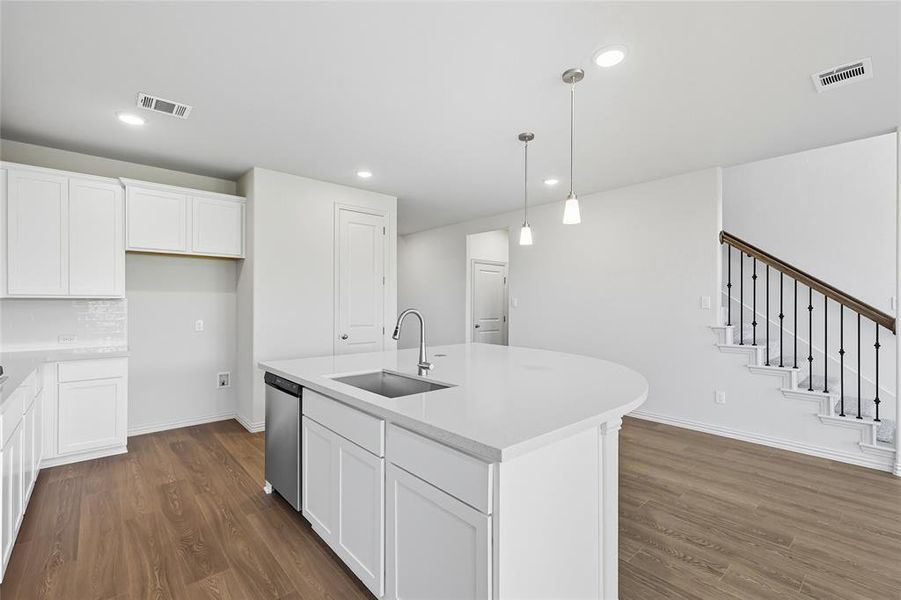 Kitchen with dark wood-style floors, white cabinets, a kitchen island with sink, hanging light fixtures, and recessed lighting Kitchen with dark wood-style floors, white cabinets, a kitchen island with sink, hanging light fixtures, and recessed lighting