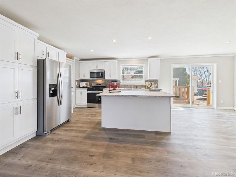 Kitchen with Natural Light – Flooded with sunlight from the adjacent sliding door and window, this kitchen is both bright and functional, perfect for casual meals or hosting.