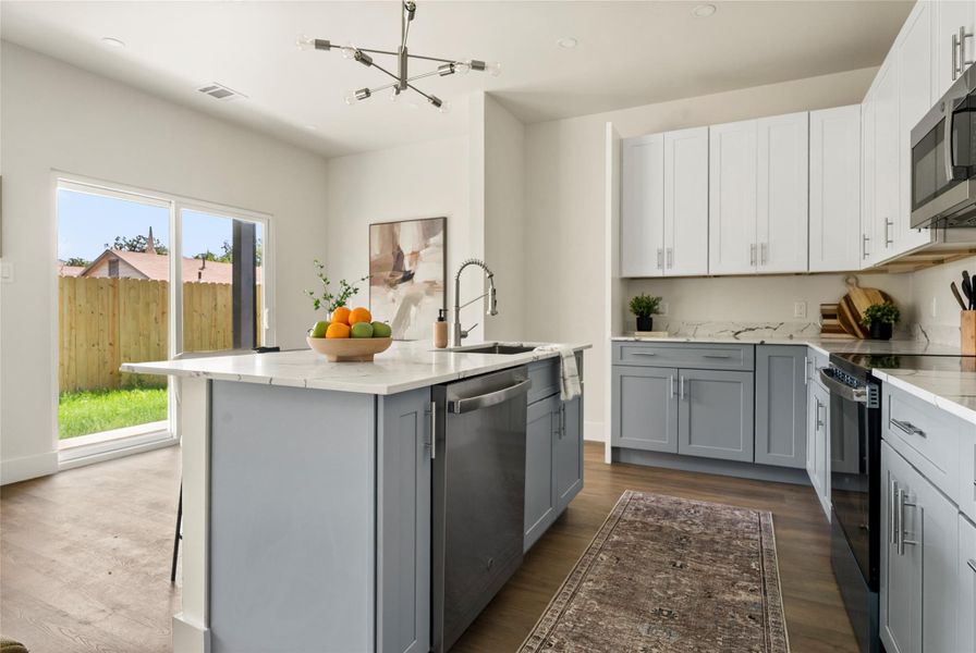 A contemporary kitchen space boasts an inviting island with a sink and a view of the private yard.