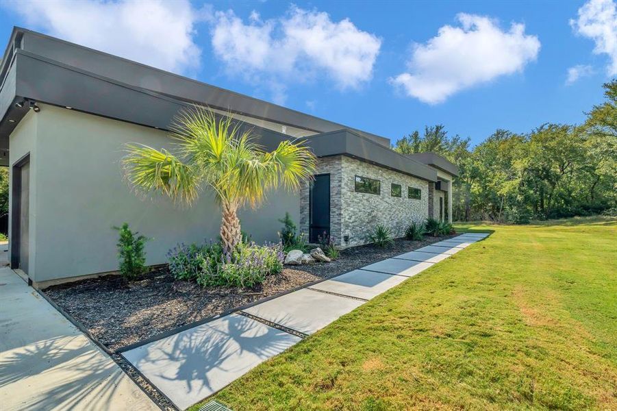 View of side of property featuring a lawn, stucco siding, and stone siding