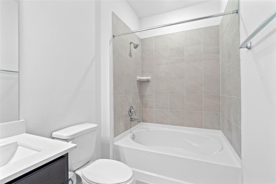 This alternate view of the primary bathroom highlighting the large tub/shower combination with tile surround, perfect for unwinding after a long day.