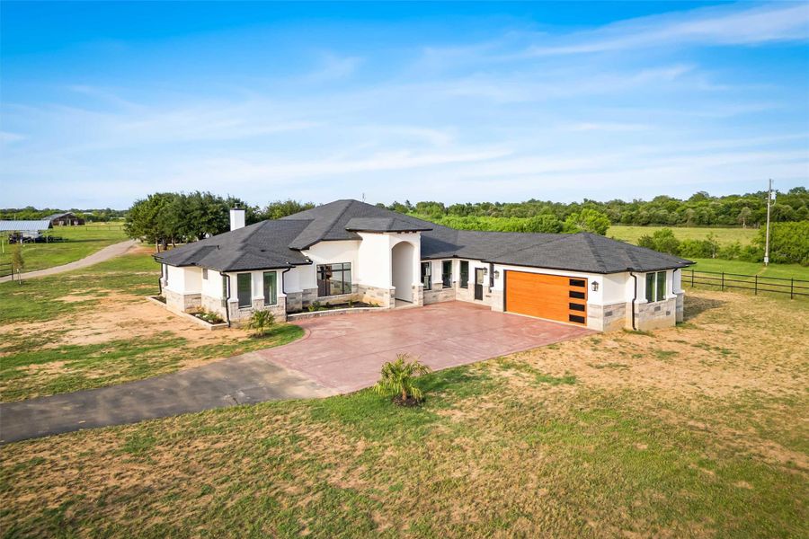 View of front facade with stone siding, an attached garage, driveway, a chimney, and stucco siding View of front facade with stone siding, an attached garage, driveway, a chimney, and stucco siding