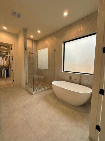 Primary Bathroom- Spa-inspired bath with freestanding soaking tub, artisan wall tile, glass walk-in shower, and brushed gold fixtures throughout. (Rendering)