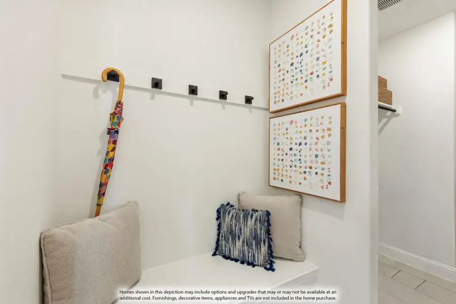 Mudroom nook with built-in bench, wall hooks, and two framed art pieces on white walls