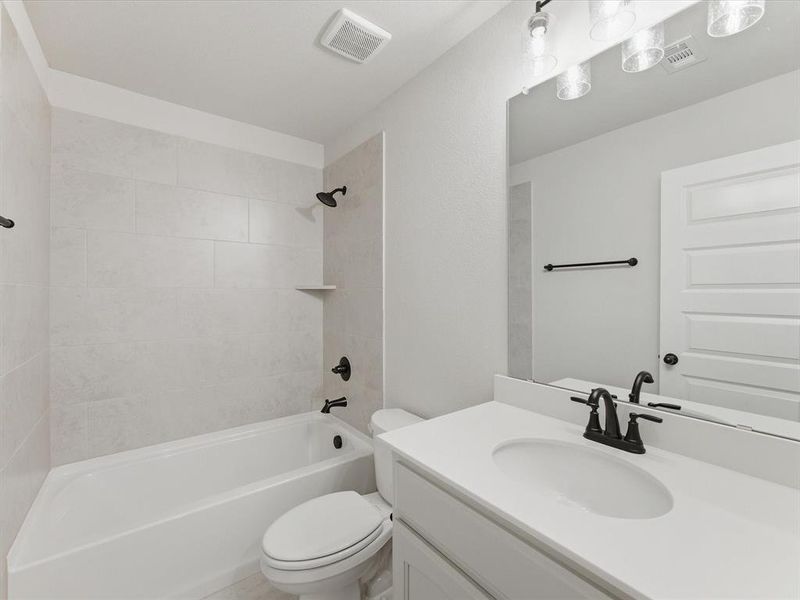Bathroom featuring a white vanity with an undermount sink, black-finish fixtures, and a large wall mirror Bathroom featuring a white vanity with an undermount sink, black-finish fixtures, and a large wall mirror