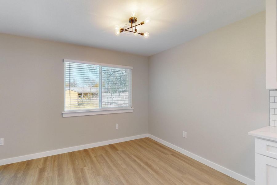 Unfurnished dining area featuring a chandelier, light wood finished floors, and baseboards