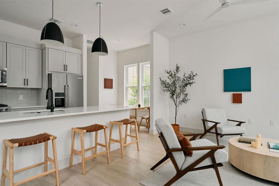 Open-concept living space featuring light wood-finish flooring, white walls, and recessed lighting