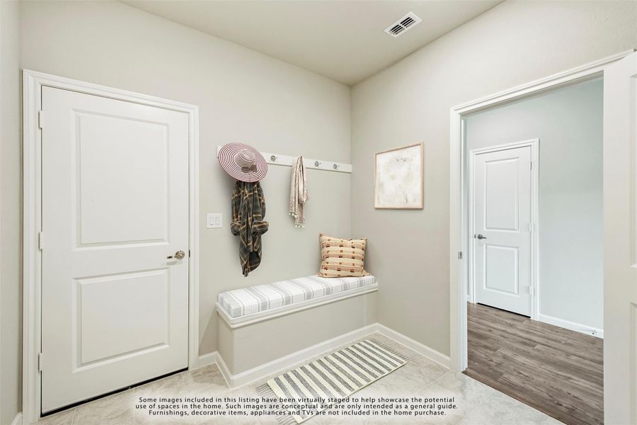 Mudroom with wall-mounted coat hooks, built-in bench, and striped area rug near entry door