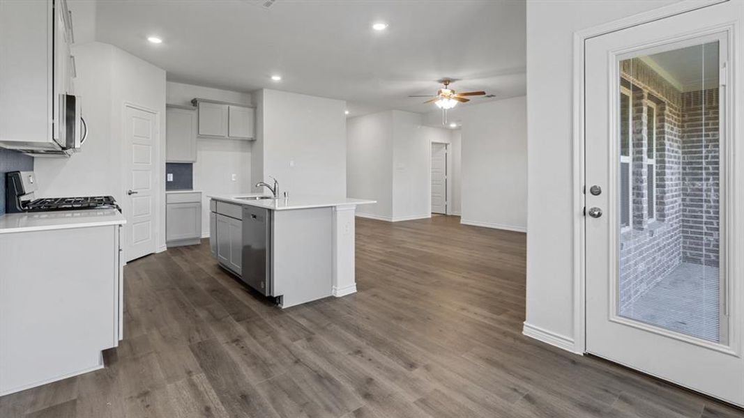 Kitchen with appliances with stainless steel finishes, a kitchen island with sink, recessed lighting, dark wood-style floors, and light stone countertops