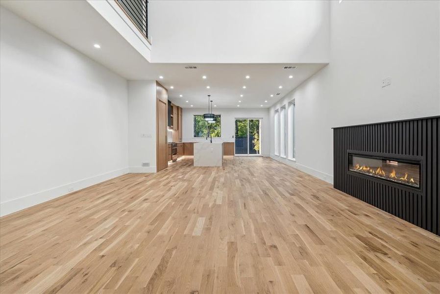 Unfurnished living room featuring a high ceiling and light wood-type flooring