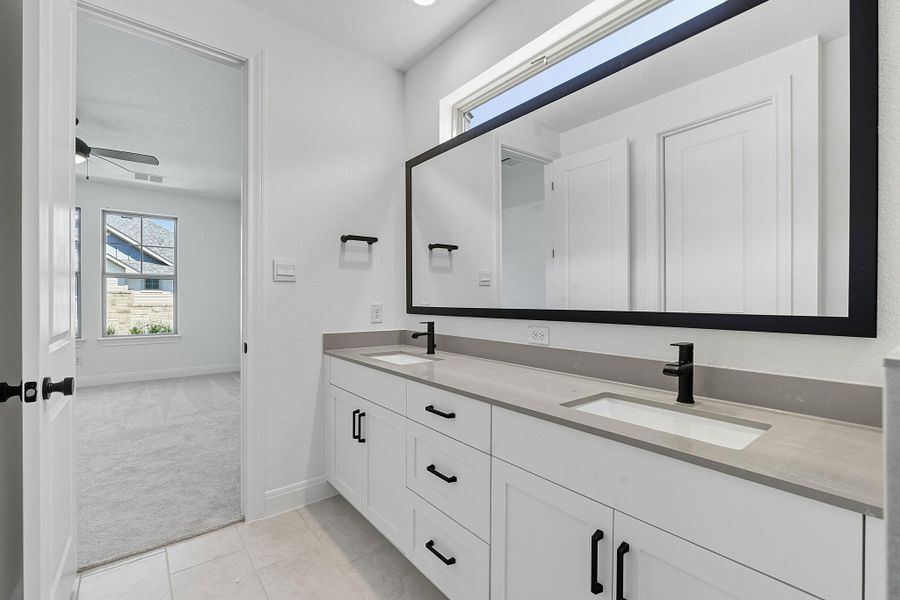 Full bathroom featuring healthy amount of natural light, double vanity, light tile patterned flooring, and light carpet
