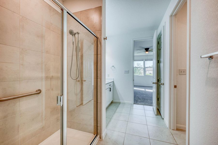 Tiled flooring runs throughout this bathroom containing a glass-enclosed walk-in shower.