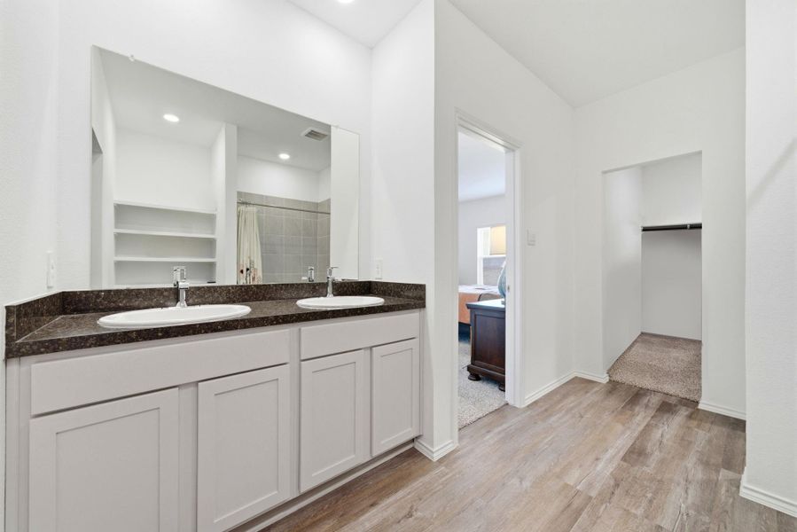 Dual-sink primary bath featuring a roomy shower, two closets, and smart shelving for maximum storage efficiency.