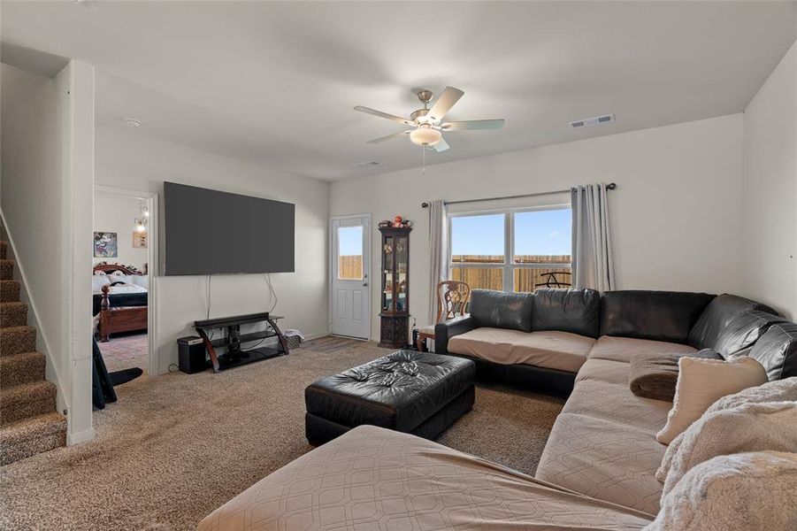 Living area featuring carpet floors, stairway, and a ceiling fan