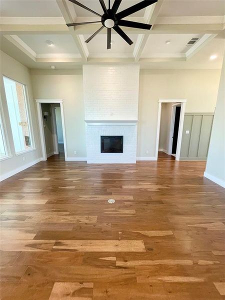 Unfurnished living room with coffered ceiling, ceiling fan, light wood-type flooring, and a fireplace