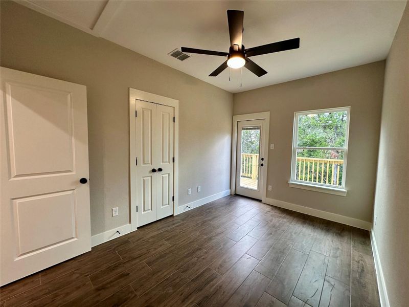 Unfurnished bedroom featuring access to exterior, dark wood-type flooring, ceiling fan, and a closet