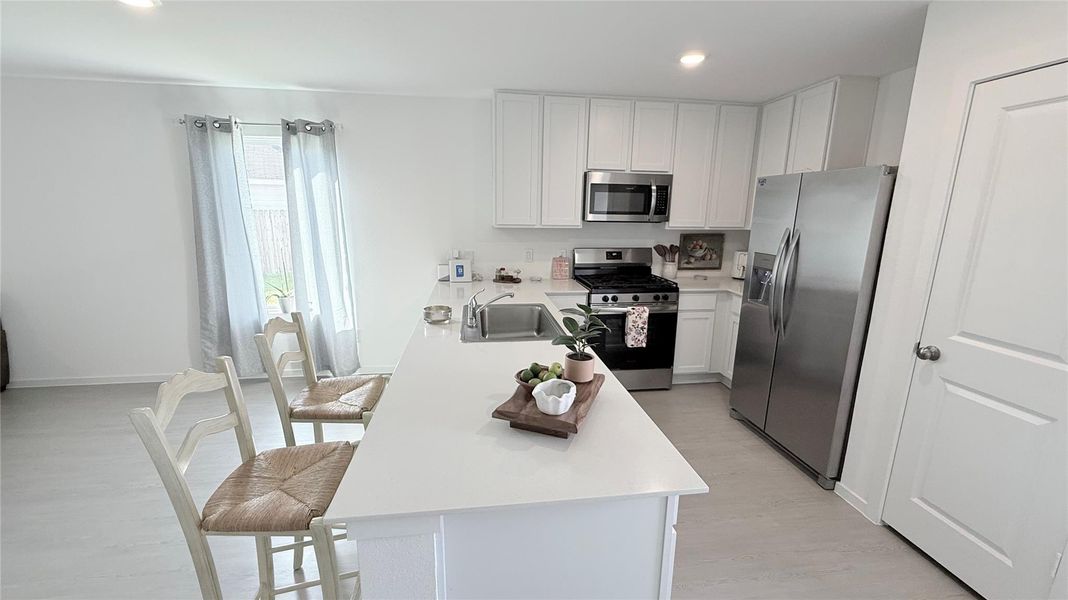 This elegant quartz countertop features subtle gray specks that perfectly match the flooring and stainless steel appliances. It offers extra seating space-perfect for casual breakfast or quick meals-while seamlessly connecting to the dining area, creating a bright and modern open layout. This elegant quartz countertop features subtle gray specks that perfectly match the flooring and stainless steel appliances. It offers extra seating space-perfect for casual breakfast or quick meals-while seamlessly connecting to the dining area, creating a bright and modern open layout.
