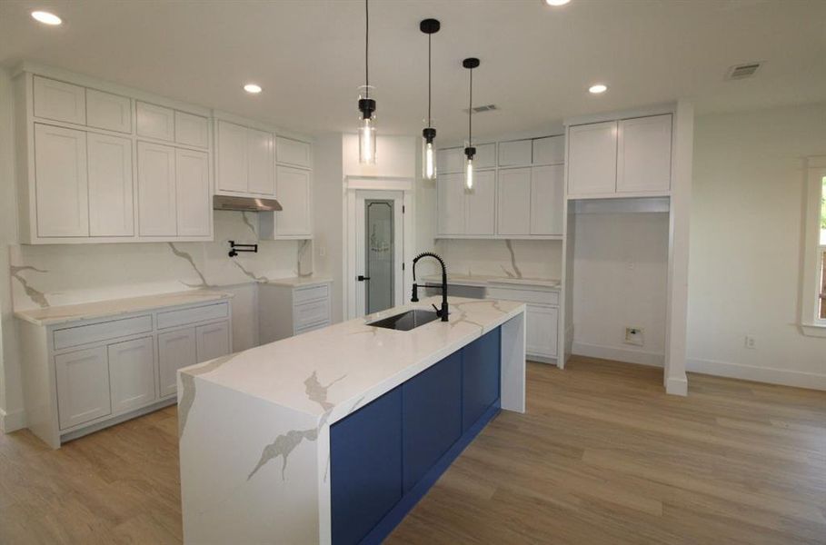 Kitchen with light stone counters, hanging light fixtures, white cabinetry, recessed lighting, and light wood finished floors Kitchen with light stone counters, hanging light fixtures, white cabinetry, recessed lighting, and light wood finished floors