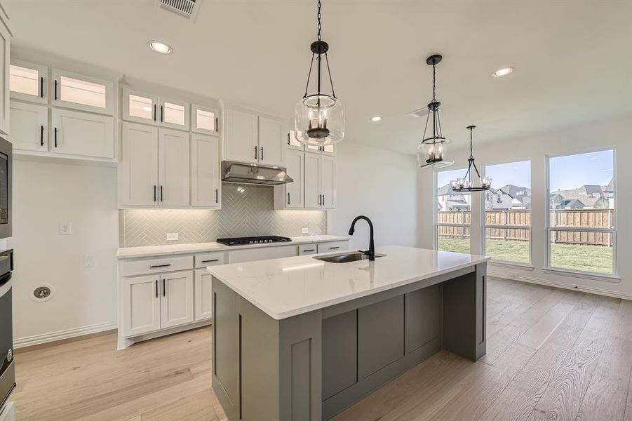 Kitchen featuring light hardwood / wood-style floors, sink, an island with sink, and white cabinets