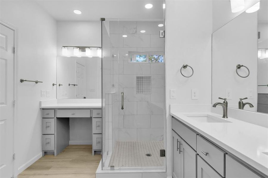 Full bath with double vanity, a shower stall, light wood-style flooring, and recessed lighting