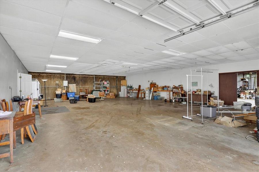 Expansive garage space featuring a concrete floor, drop ceiling with fluorescent lighting, and two overhead garage door
