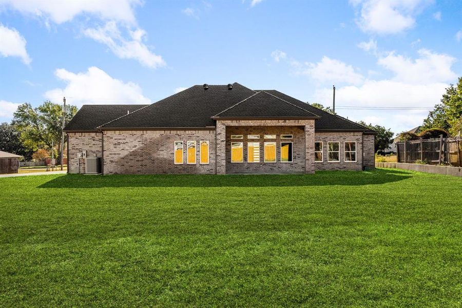 Back of house featuring a lawn and central air condition unit