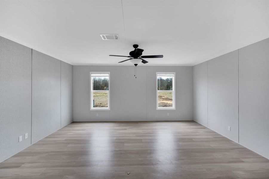 Spare room with a decorative wall, light wood-style flooring, and ceiling fan