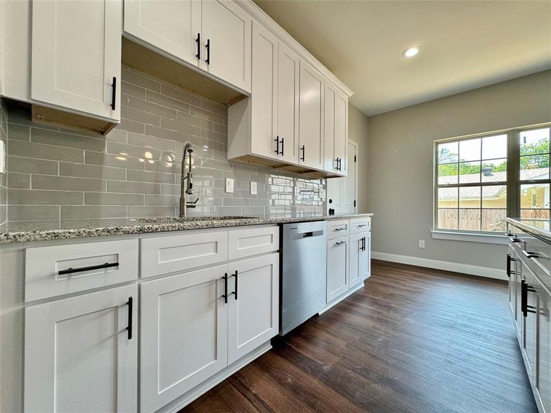 Kitchen with sink, decorative backsplash, dark hardwood / wood-style floors, white cabinetry, and dishwasher