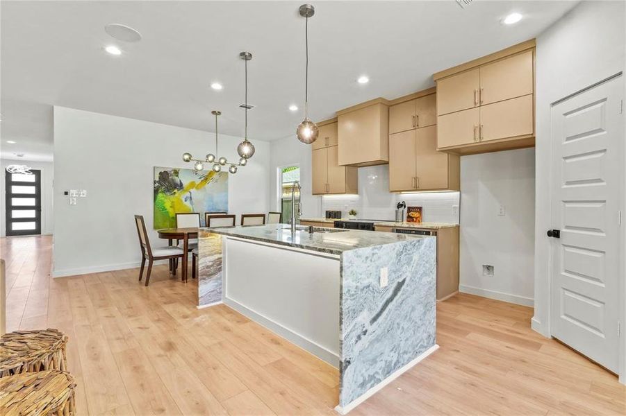 Kitchen featuring light stone countertops, a center island with sink, recessed lighting, decorative light fixtures, and light wood finished floors Kitchen featuring light stone countertops, a center island with sink, recessed lighting, decorative light fixtures, and light wood finished floors