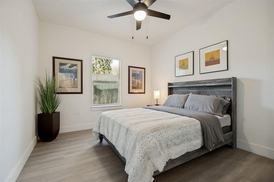 Vaulted ceiling bedroom with light wood-finish flooring, a contemporary ceiling fan, and white walls Vaulted ceiling bedroom with light wood-finish flooring, a contemporary ceiling fan, and white walls