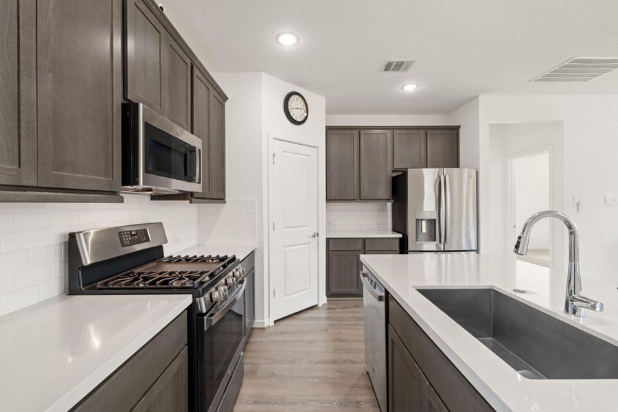 You will love the details of this kitchen! It's finished with a large single basin sink, quartz countertops, a walk-in pantry, and sleek white tile backsplash. There is plenty of storage and counterspace making this kitchen every chef's dream!