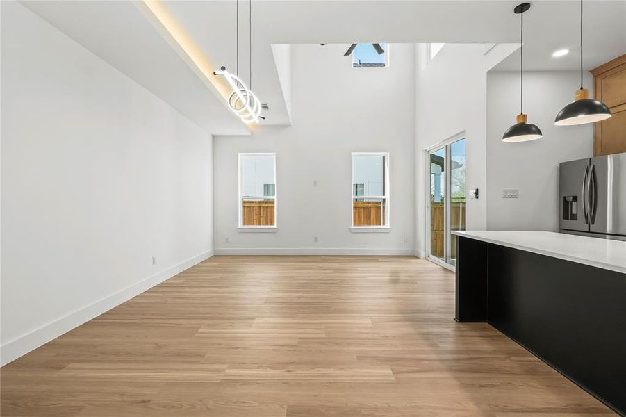Unfurnished dining area featuring light wood-style flooring, a high ceiling, recessed lighting, and ceiling fan