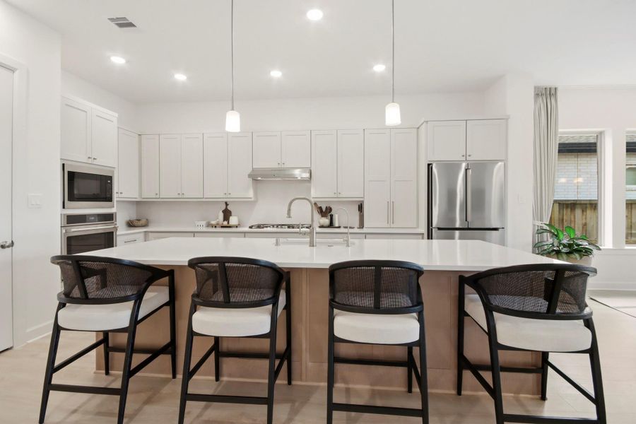 Stylish kitchen featuring a generous island, pendant lighting, and stainless steel appliances, offering a functional and inviting space for meal preparation and entertaining.