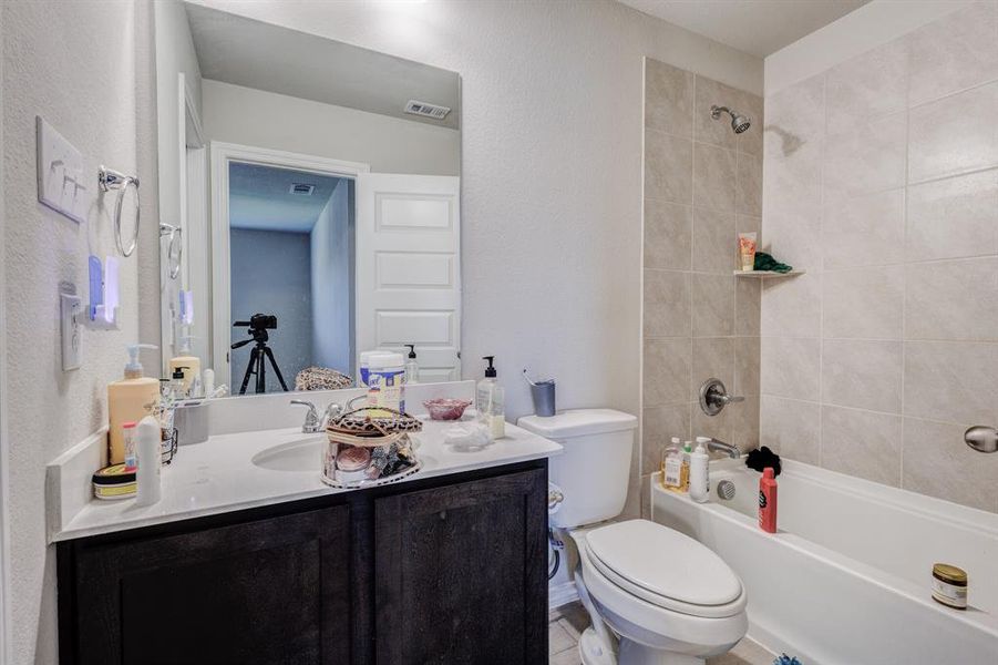 Full bathroom featuring a textured wall, vanity, and shower combination Full bathroom featuring a textured wall, vanity, and shower combination