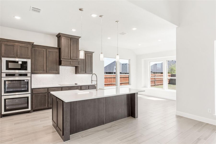 Kitchen with dark brown cabinets, center island, white countertops, and stainless steel double oven and microwave Kitchen with dark brown cabinets, center island, white countertops, and stainless steel double oven and microwave