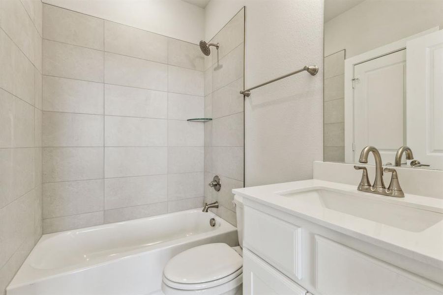 Full bathroom with tiled shower / bath, vanity, and toilet