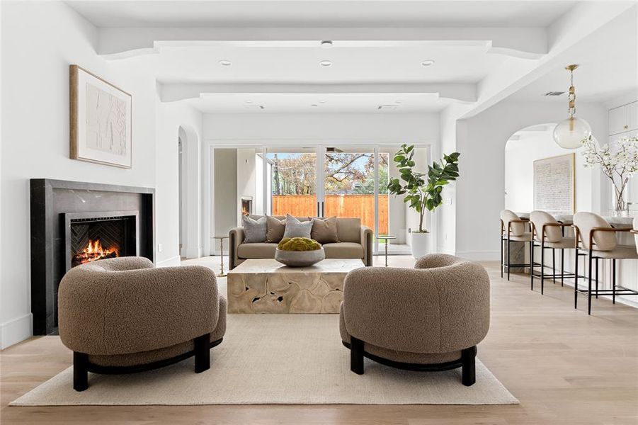 Living area with light wood-type flooring, a premium fireplace, arched walkways, and recessed lighting