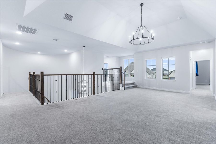 Empty room featuring a chandelier and carpet flooring