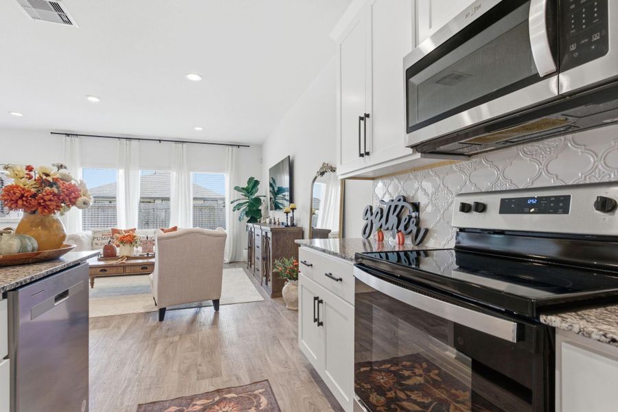 Gourmet kitchen featuring recently upgraded backsplash, granite countertops, stainless steel appliances, and a large eat-in island. Gourmet kitchen featuring recently upgraded backsplash, granite countertops, stainless steel appliances, and a large eat-in island.