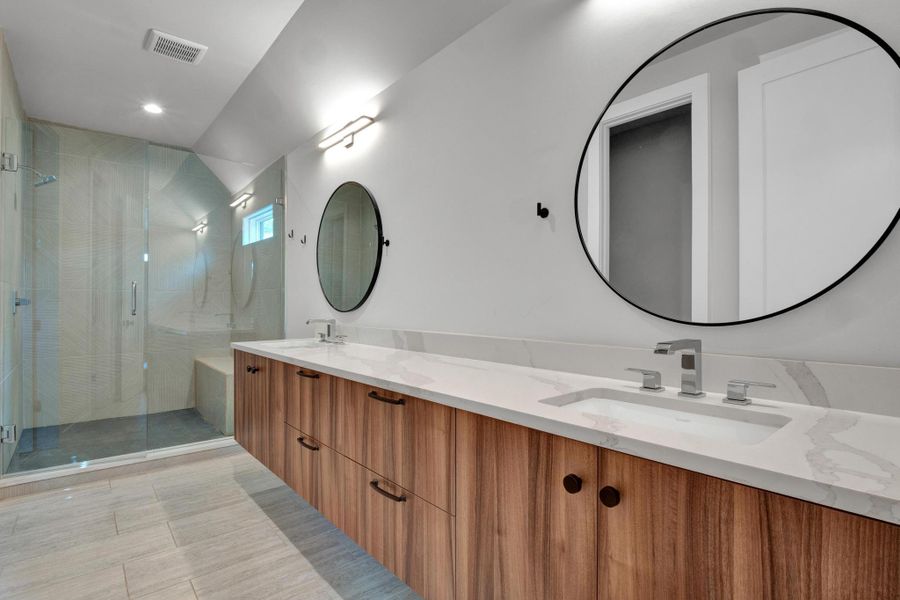 Bathroom featuring double vanity and a stall shower