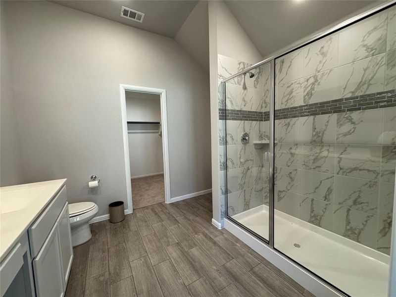 Spacious bathroom featuring a glass-enclosed shower with marbled tile, a decorative tile accent band, and a built-in shower niche Spacious bathroom featuring a glass-enclosed shower with marbled tile, a decorative tile accent band, and a built-in shower niche