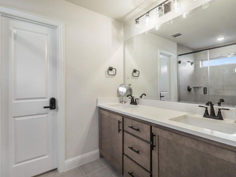 Bathroom with double vanity, a stall shower, and light tile patterned floors Bathroom with double vanity, a stall shower, and light tile patterned floors