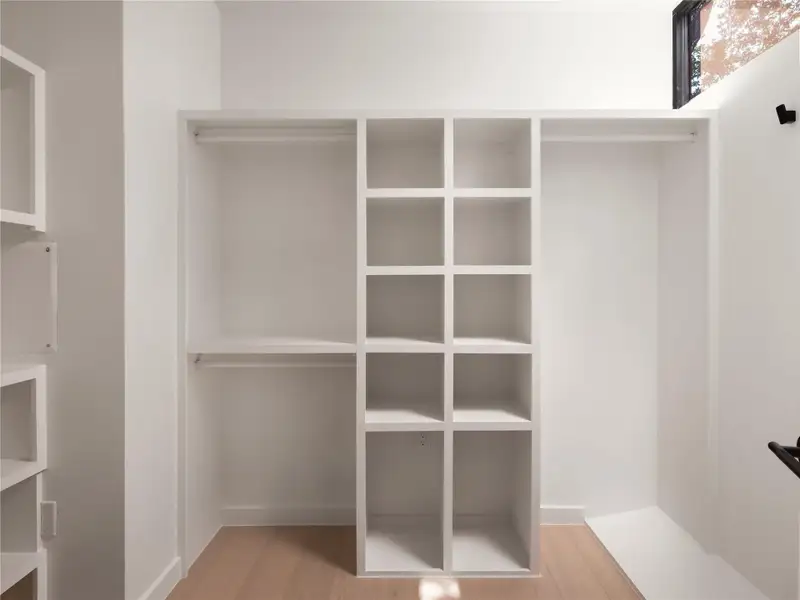 A streamlined primary bedroom's walk-in closet offers ample storage with built-in shelving and hanging space. A streamlined primary bedroom's walk-in closet offers ample storage with built-in shelving and hanging space.