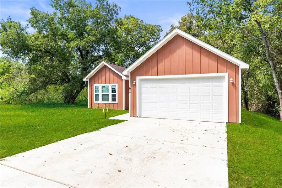 View of front of house with board and batten siding, a front yard, and a garage View of front of house with board and batten siding, a front yard, and a garage