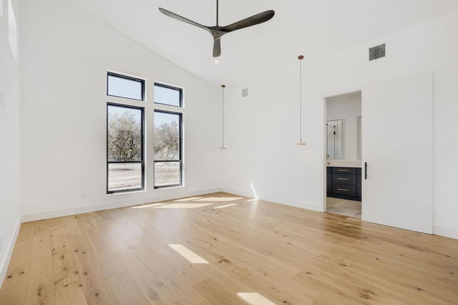 Empty room with light wood-type flooring, vaulted ceiling, and a ceiling fan Empty room with light wood-type flooring, vaulted ceiling, and a ceiling fan
