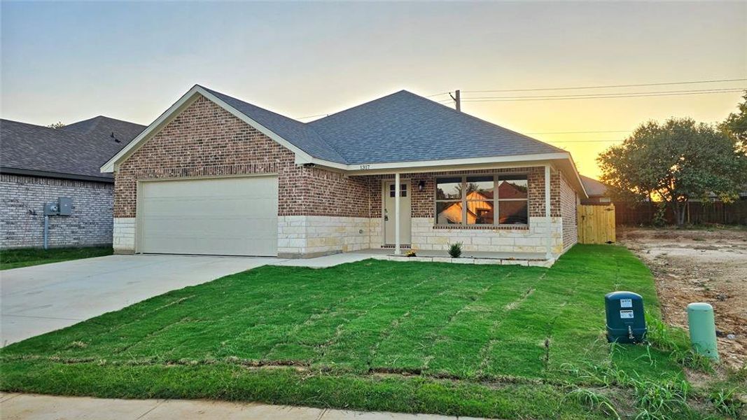 View of front of property with roof with shingles, driveway, brick siding, a garage, and stone siding