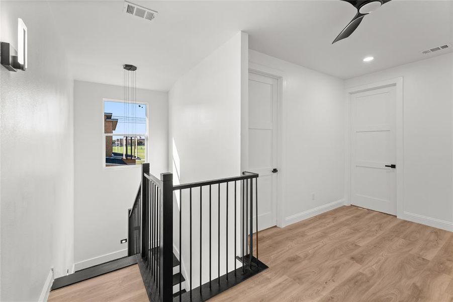 Hall featuring light wood-type flooring, an upstairs landing, and recessed lighting